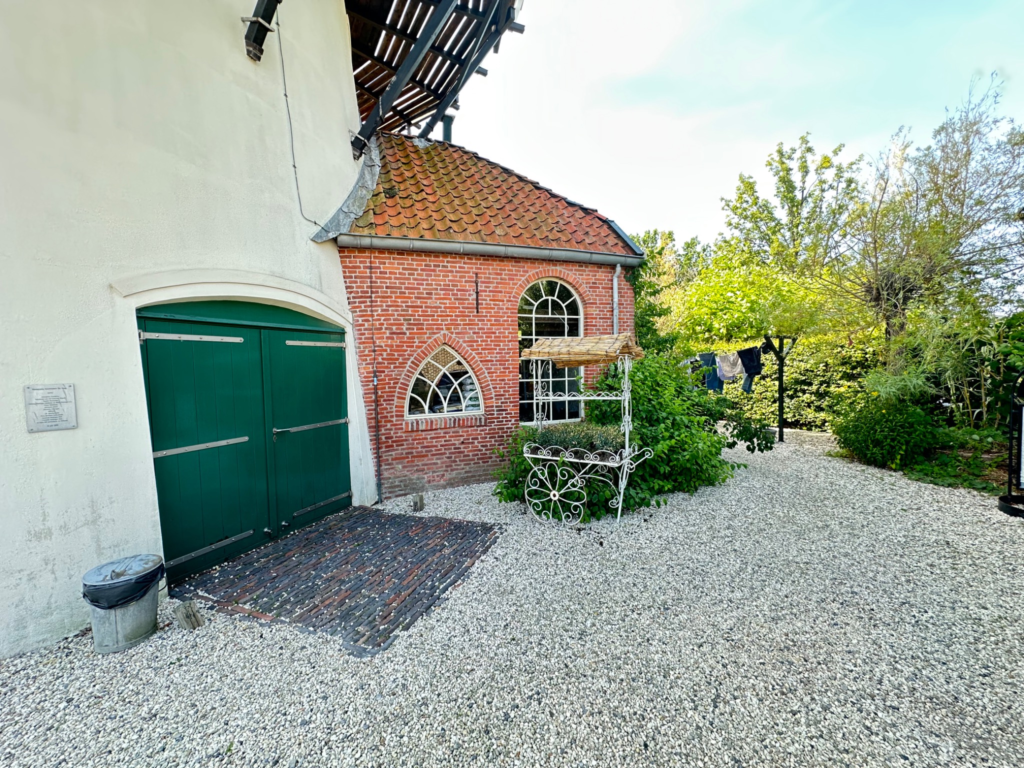 De groene molenpoort en de gebouwen en tuin achter Molen De Hoop.