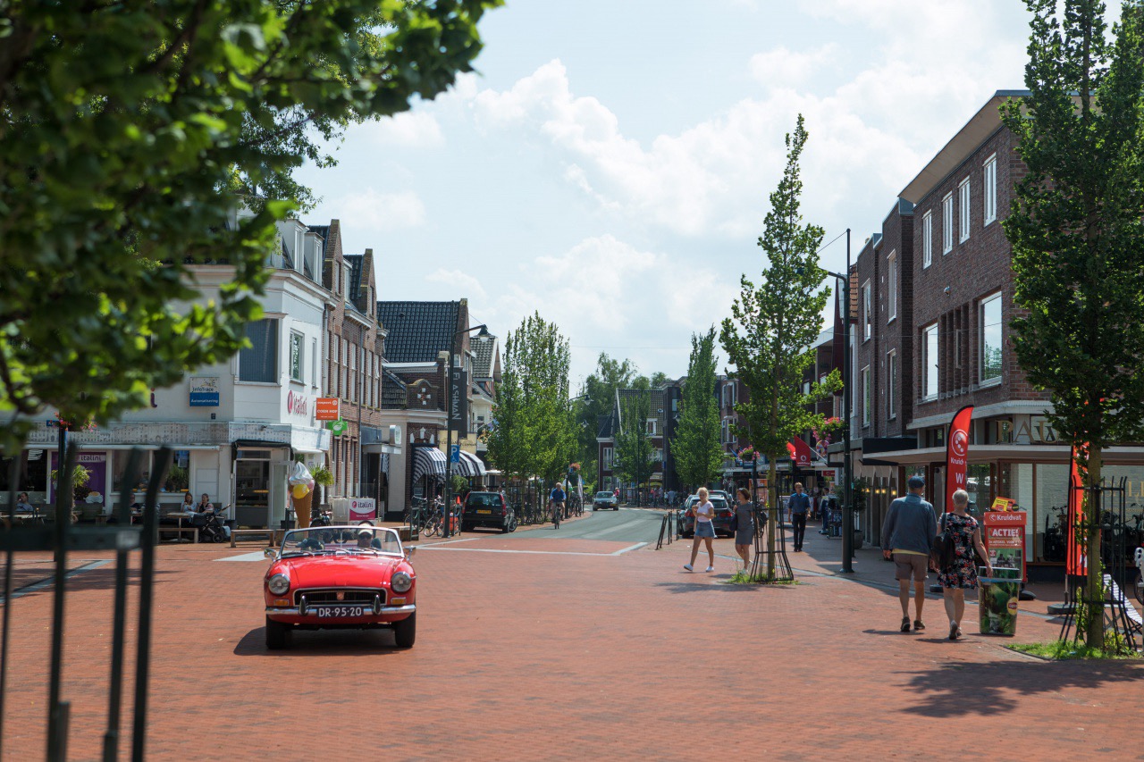 Een straat in het centrum van Haren, met winkels, bomen en terrassen.