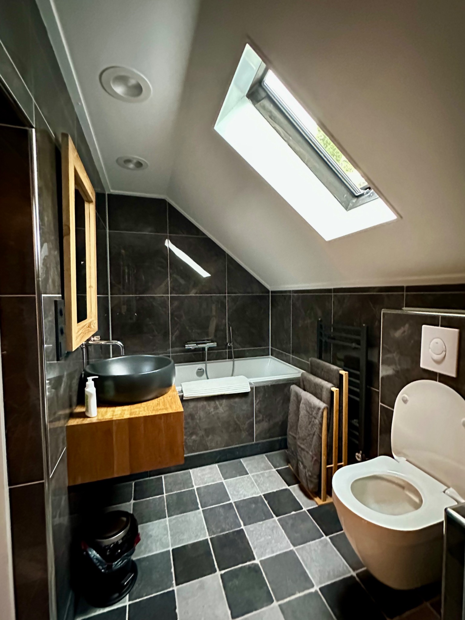Het ligbad onder het dakraam, met wastafel en toilet in de badkamer.