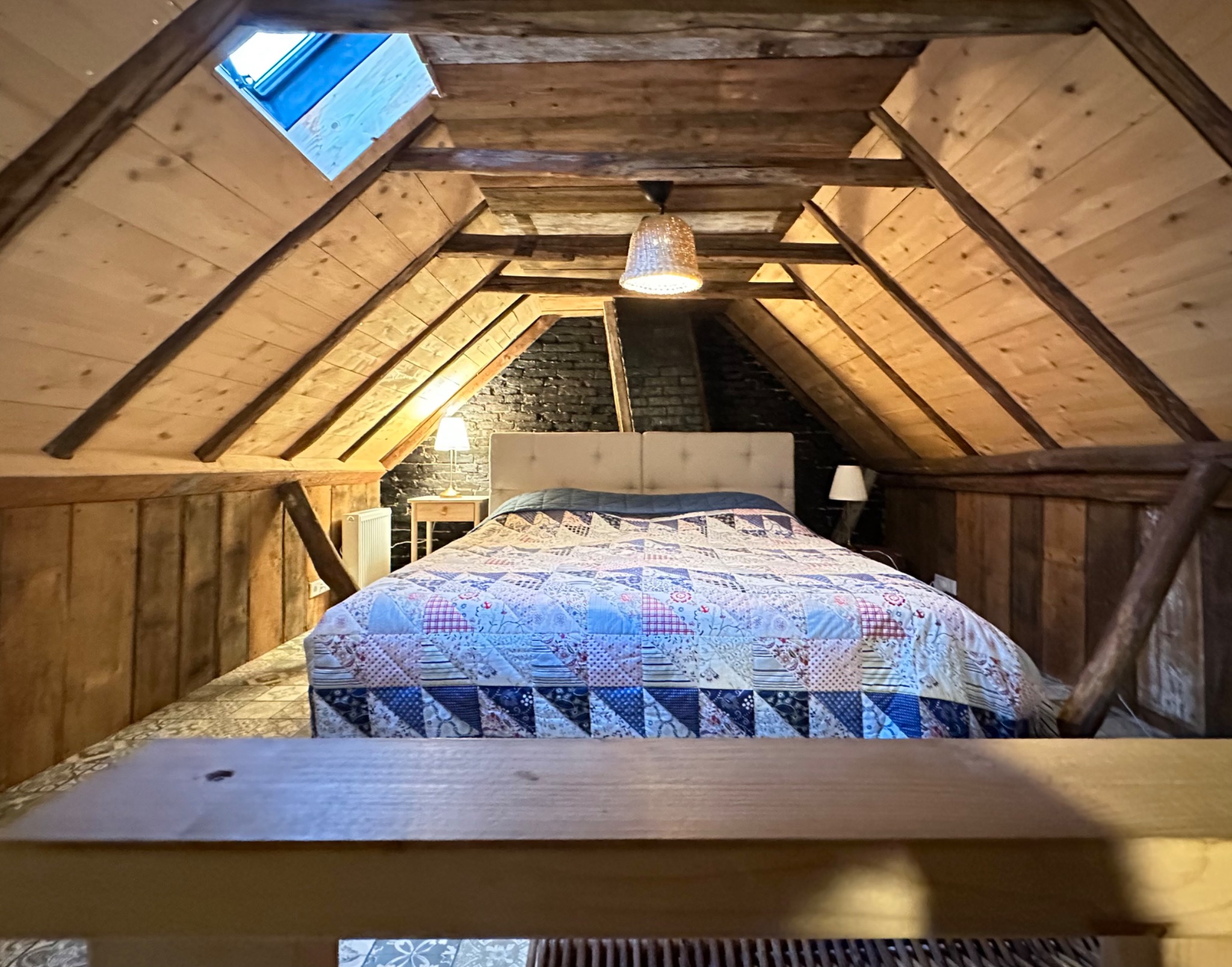 Het tweepersoonsbed op de slaapvide onder het houten dak.